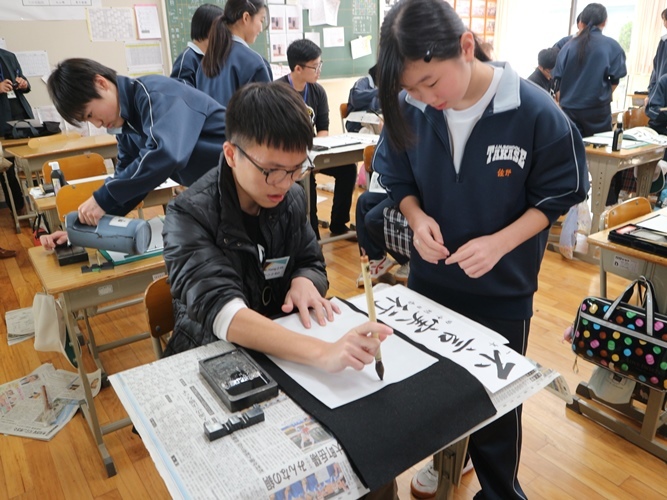 マレーシアの高校生が高瀬中学の生徒に書道を教わっている